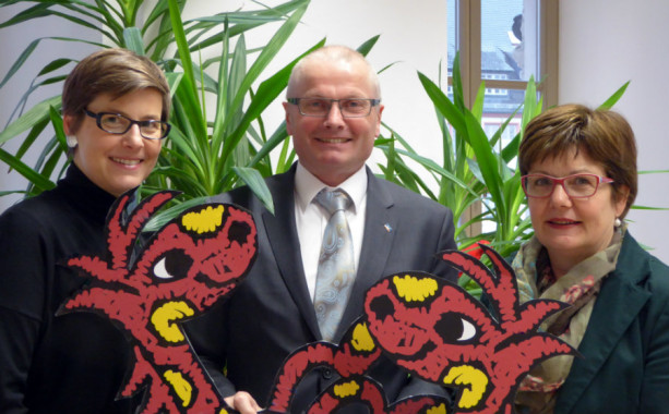 Schwungvoll und in neuem Design zeigt sich das Jugendbuchwochen-Maskottchen *Leselotte“ zusammen mit (v.l.) Anja Flicker (Stadtbücherei), Helmut Heitzer (VR-Bank) und Angelika Riedel (Stadtbücherei) (Foto: Stadtbücherei).